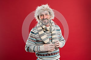 Keeping him warm. A winter ensemble protects him from cold. Bearded man accessorizing sweater with hat and scarf. Mature