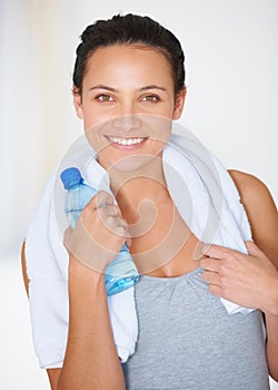Keeping hydrated to get the most out of my workout. Portrait of a young woman in gymwear with a bottle of water.