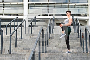 Keeping those muscles flexible. Young male runner athlete training and exercising outdoors in the city. Warm up firstly photo