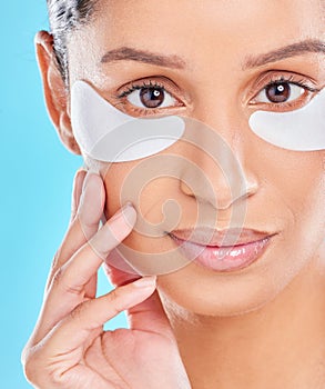 Keeping my skin looking young. Studio portrait of an attractive young woman wearing under eye patches against a blue