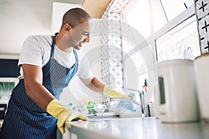 Keeping my space clean makes me feel good. a young man cleaning a kitchen at home.