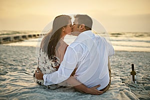 Keeping the romance alive. High angle shot of an affectionate young couple kissing while sitting on the beach.