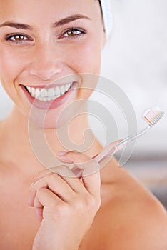 Keeping this smile shining bright. A cute woman holding a toothbrush and smiling at the camera.