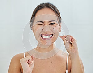 Keeping up with my dental hygiene. Shot of a young woman flossing her teeth in a bathrroom at home.