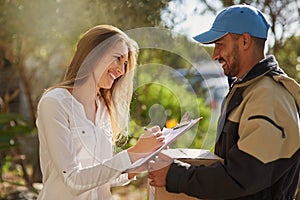 He keeps his customers smiling. a courier delivering a package to a smiling young woman at home.