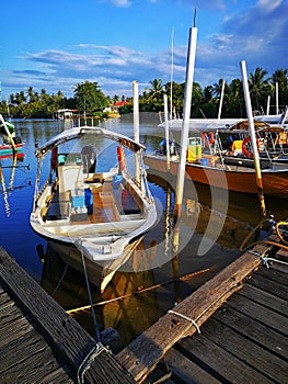 Kelantan, Malaysia -fishing boat near wooden jetty. Beautiful malaysian landscape. Sunset reflection in the water.