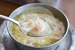 Kelle Paca soup in a bowl / plate with spoon and lemon on wooden table. Traditional soup of Gaziante