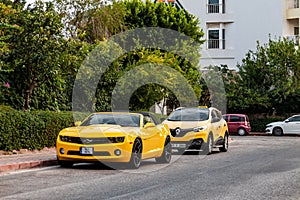 Kemer, Turkey - 08,31, 2021: Bright yellow Chevrolet Camaro with black stripes standing at car parking near luxury hotel under