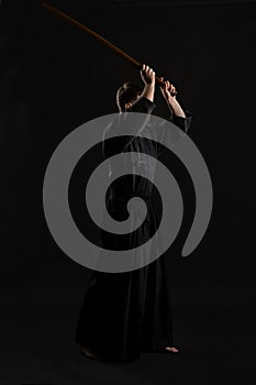 Kendo guru wearing in a traditional japanese kimono is practicing martial art with the shinai bamboo sword against a