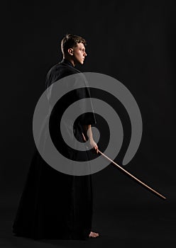 Kendo guru wearing in a traditional japanese kimono is practicing martial art with the shinai bamboo sword against a