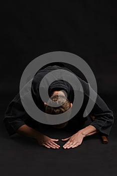 Kendo guru wearing in a traditional japanese kimono is practicing martial art with the shinai bamboo sword against a