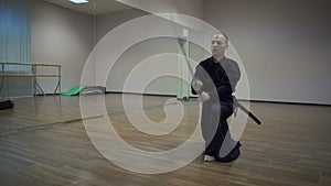 Kendoka master makes swings by katan sword in pride, performs kata in the sports hall with mirrors