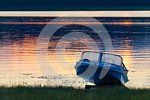 Kenozersky National Park, Russia. An old blue aluminum motorboat called `Kazanka` on the lake shore at sunset. Blue boat on the