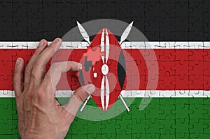 Kenya flag is depicted on a puzzle, which the man`s hand completes to fold