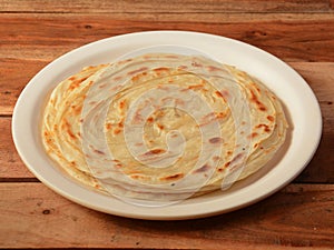 Kerala Paratha, a layered flat bread using wheat flour, popular dish in south India. isolated over a rustic wooden background,