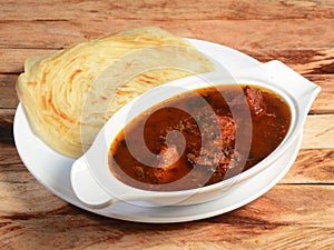 Kerala paratha / parotta, layered flat bread made from maida or whole wheat flour. Served with spicy kerala chicken curry,