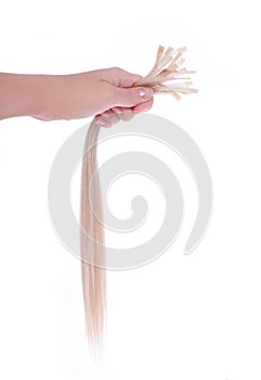 Keratin capsules on blonde hair extensions in hand photo