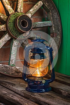 Kerosene lamp against the background wagon wheel