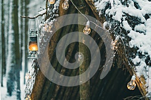 Kerosene lamp and garlands hanging on survival shelter in winter forest