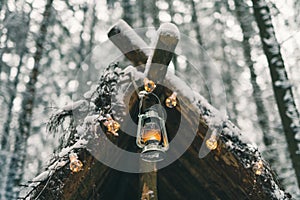 Kerosene lamp and garlands hanging on survival shelter in winter forest