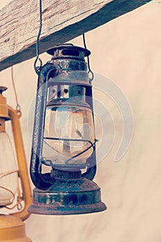 Kerosene lamp or lantern weighs on a wooden beam. vertically