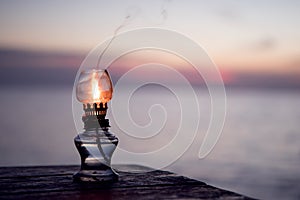Kerosene lamp on sunset beach back