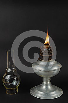 Kerosene or oil lamp with burning wick against Gray background