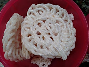 Kerupuk or crackers are placed in a pink container. One of the snacks in Indonesia.