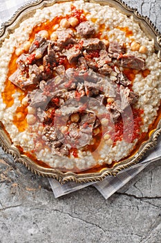 Keskek or kashkak, kashkek, or keske, is a ceremonial lamb meat and wheat chickpeas stew closeup on the plate. Vertical top view