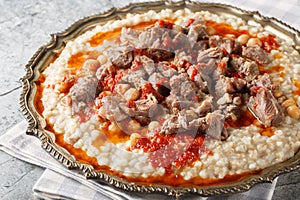 Keskek or kashkak stew made of meat and wheat, with butter and red pepper sauce closeup on the plate. Horizontal