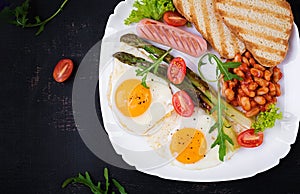 Keto breakfast. Breakfast. Fried eggs, bread toast, green asparagus, beans and sausage on white plate. Top view, flat lay