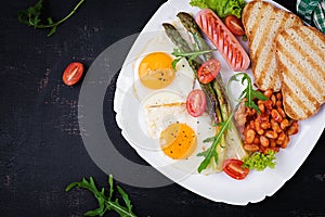 Keto breakfast. Breakfast. Fried eggs, bread toast, green asparagus, beans and sausage on white plate. Top view, flat lay