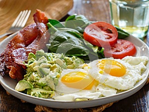 Keto breakfast plate with eggs bacon and mashed avocado