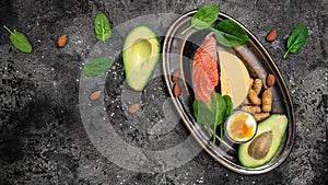 Keto diet food, salmon, avocado, cheese, egg, spinach and nuts. Ketogenic low carbs diet concept. Ingredients for healthy foods