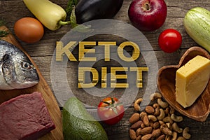 Keto diet low carbs food. Healthy products. Diet concept. Vegetables, fish, meat, nuts, seeds, tomato, apple, cheese on a brown ba photo
