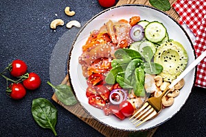 Keto diet salad with salmon, shrimp, avocado, spinach, cucumber, tomato, cashew, sesame. Low-carbohydrate lunch rich in healthy