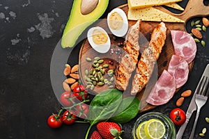 Almuerzo o la parrilla salmón verduras cocido huevos Agua cal nueces jamón queso sobre el oscuro 