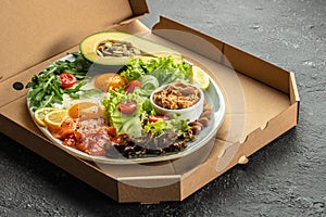 Keto plate of healthy food in a pizza box. Concept of healthy eating or fast food