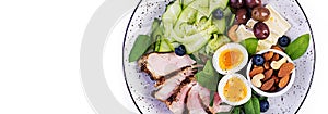 Ketogenic diet. Keto brunch. Boiled egg, pork steak and olives, cucumber, spinach, brie cheese, nuts and blueberry. Banner. Top