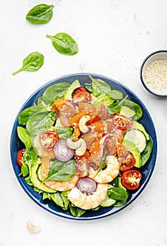 Ketogenic diet salad with salmon, shrimp, avocado, spinach, cucumber, tomato, cashew nuts, sesame. Low-carbohydrate lunch rich in