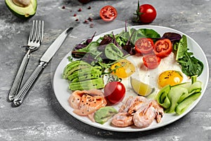 Ketogenic Low Carbohydrate Breakfast salmon, boiled shrimps, prawns, fried eggs, fresh salad, tomatoes, cucumbers and avocado. top