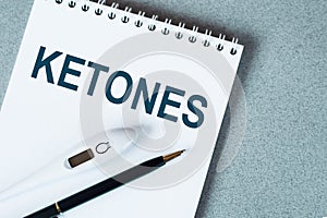 KETONES text written on notepad with a black pencil and electronic thermometre on it on blue surface Medical concept