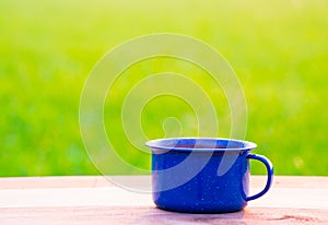 Kettle, blue enamel, and coffee mugs On an old wooden floor, Blurred background of rice fields at sunrise