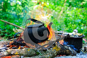 Kettle on campfire. Camping or hiking. Background with selective focus