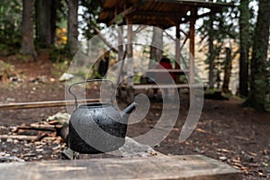 Kettle with a mug in a tourist camp. outdoor recreation in the forest