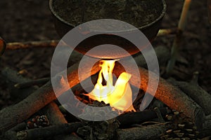 A kettle pot over a campfire.