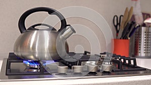 Kettle stands on a gas stove. The flame is blue.