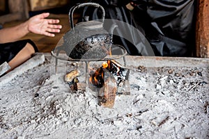 The kettle, which has black and dirty stains from wood fuel sticks