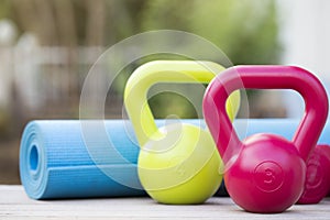 Kettlebell, dumbbell and yoga mat on table