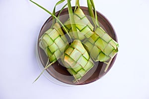 ketupat in earthenware plate isolated on white background. Ketupat Rice Dumpling is food served when idhul fitri eid mubarak.